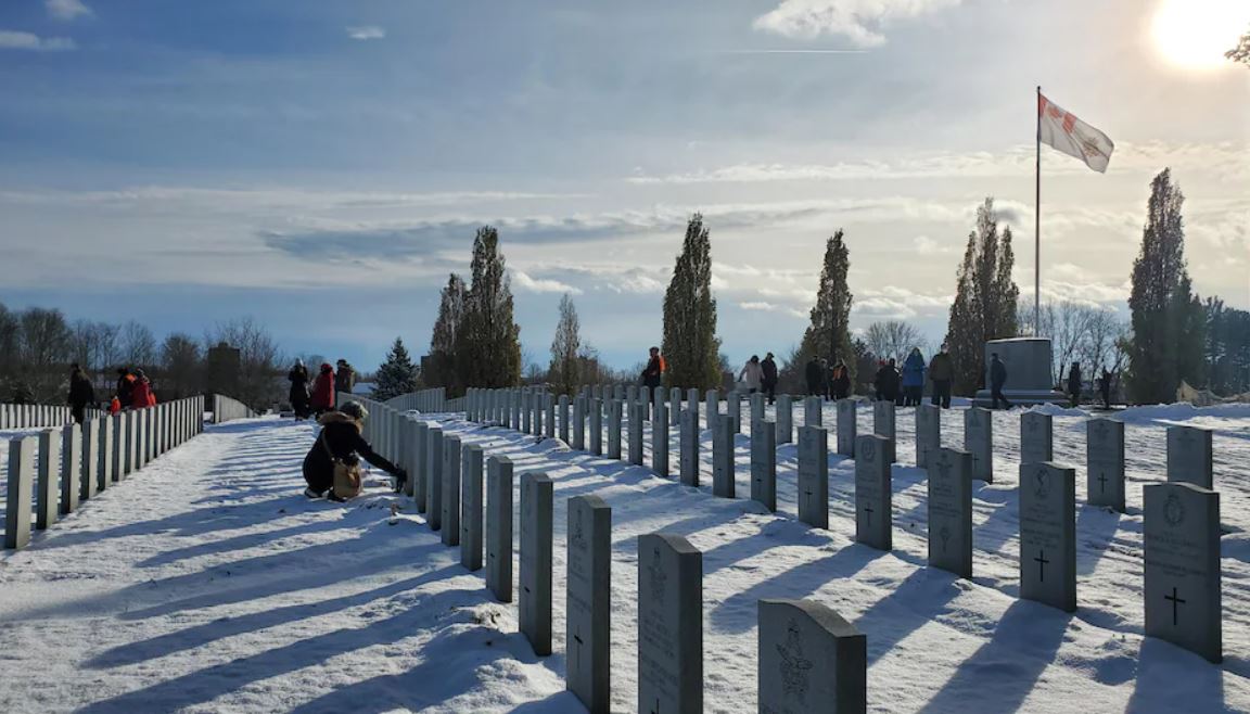 Mother laying a wreaths at a headstone of a military member